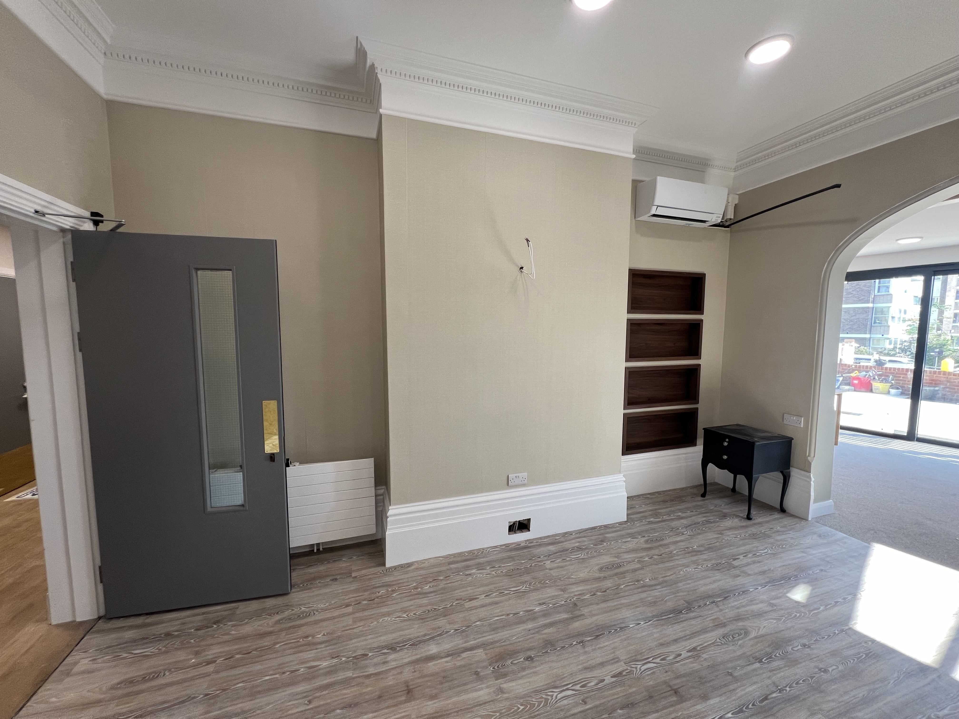 Modern interior with warm taupe walls, ornate white cornicing, and built-in shelving